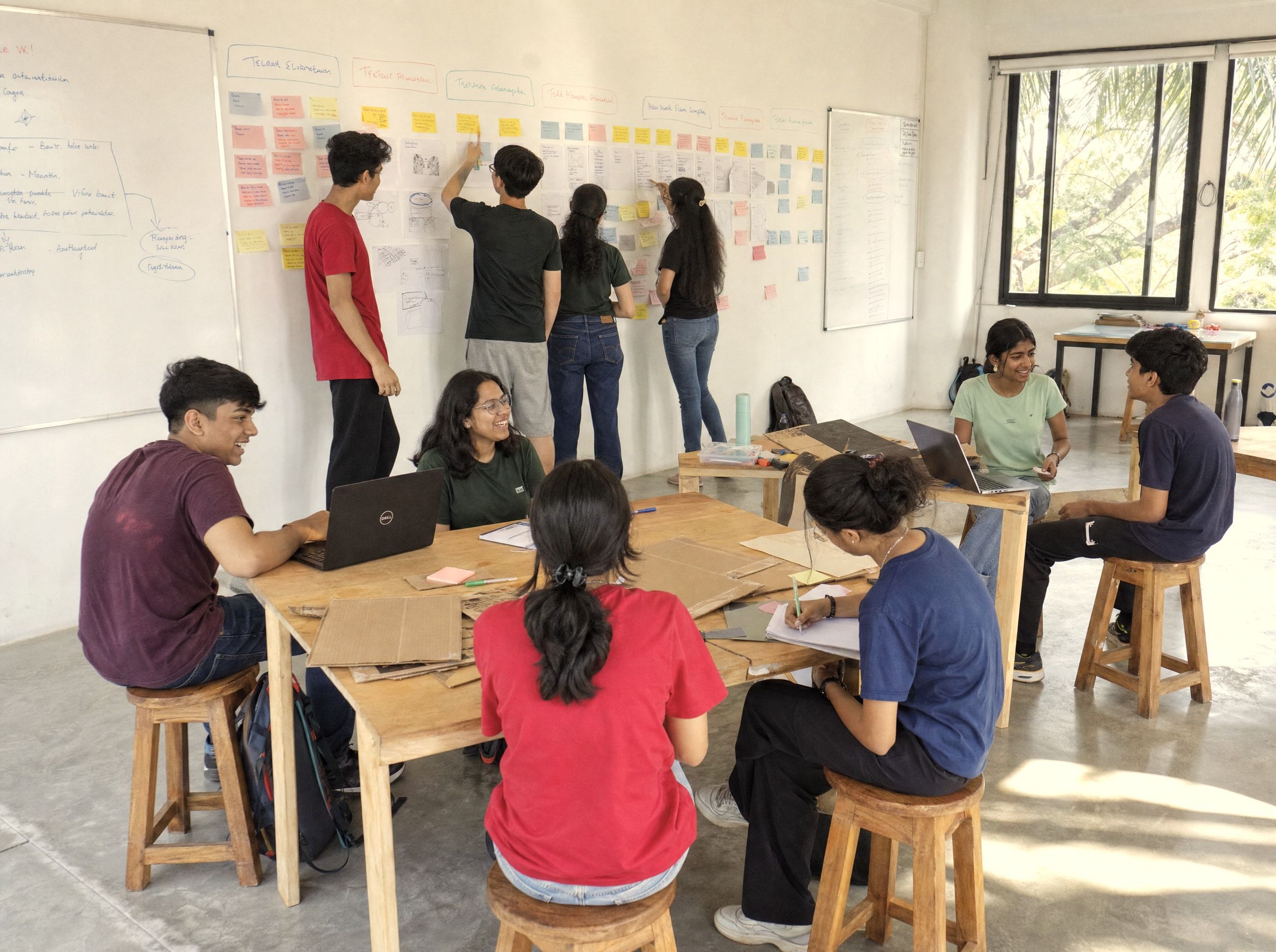 Students at work in the Early Movers room, the wall covered in sticky notes and sketches